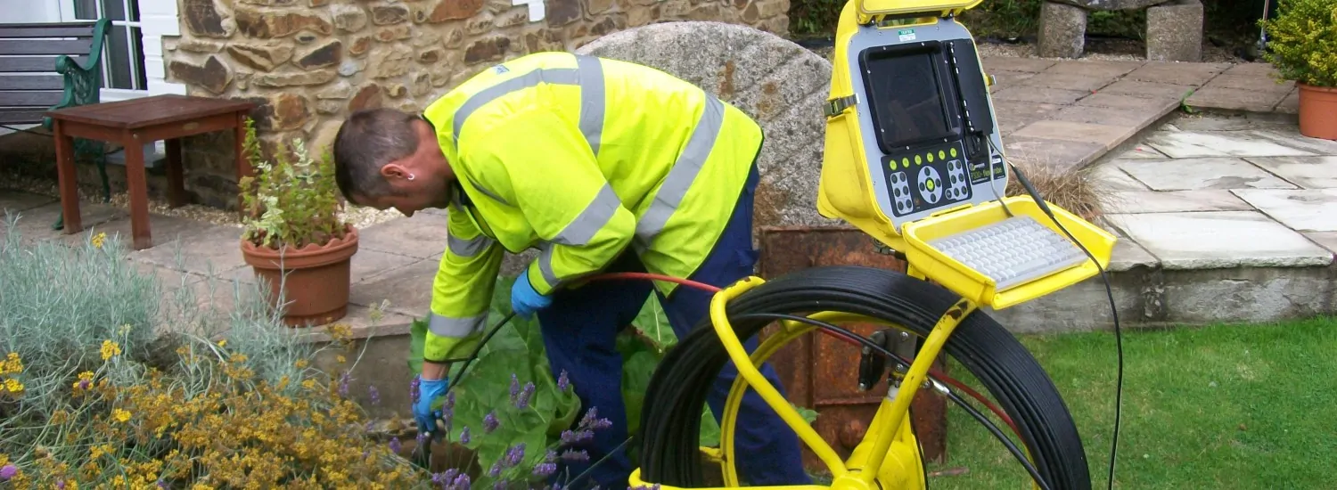 Close-up of a drainage pipe being inspected outdoors in a UK residential garden
